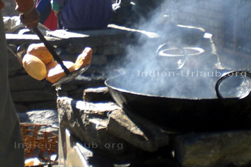 Hier auf dem Bild deutlich zu sehen wie der indische Koch mit einer Kelle die ausgebackenen goldgelben Brote aus der heißen Pfanne holt. Wichtig bei den ayurvedischen Speisen - das man Zutaten aus biologischem Anbau zum kochen verwendet.