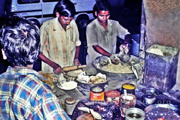 Diese drei Typen auf diesem Bild bereiten gerade ein Ayurvedisches Essen zu, der Indische Koch im Vordergrund bereitet den Fisch, der indische Koche in der Mitte mit dem Nudelholz das Chapati-Brot und der auf der im rechten Bildrand die Linsen. Das Bild sieht so aus weil ich das mit einem Blitz fotografierten musste es war schließlich abends.