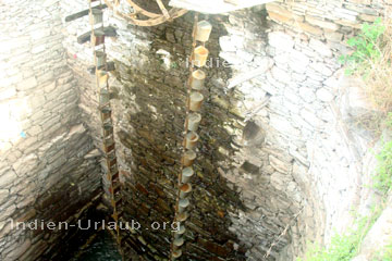 Etwa 20 Meter tiefer Brunnen in Rajasthan wo in etwa 50 Eimer über ein Rad wie bei einem Förderband gezogen werden.