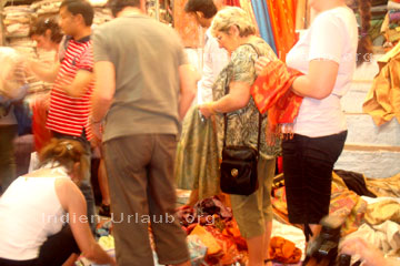 Touristen die auf einem indischen Textilien Markt indische Mode kaufen.