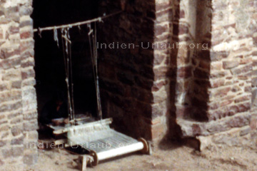 Indischer Webstuhl für die ärmere Bevölkerung Indiens. Da wird jedes ungenutzte Bauwerk zur Mini-Fabrik für Textilien umfunktioniert wie hier auf dem Bild zu sehen ist.