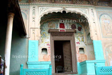 Eingang in ein prunkvolles Haveli der reich mit Motiven der indischen Religion bemalt ist in Mandawa bei der Rajasthan Rundreise und durch Indien.