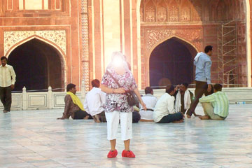 Touristin mit rosa Farben Überschuhen auf den Marmorplatten bei der Besichtigung vom Taj Mahal.